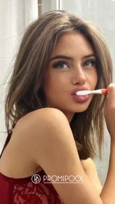 a woman brushing her teeth with an electric toothbrush