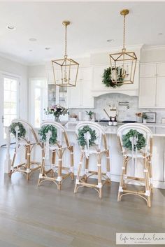 a kitchen filled with lots of white counter top space and chairs covered in wreaths