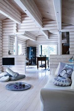 a living room filled with white furniture and wooden walls on top of a hard wood floor