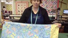 a woman holding up a large piece of fabric in front of a sewing machine and quilting machines