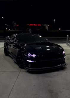 a black car parked in a parking lot at night