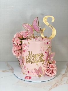 a pink birthday cake decorated with flowers and butterflies