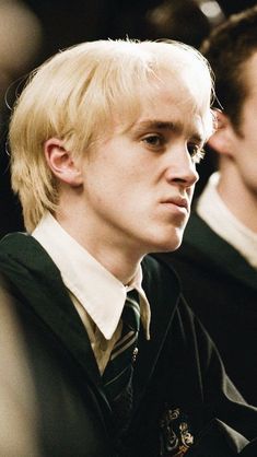 a young man with blonde hair wearing a harry potter uniform and looking off to the side