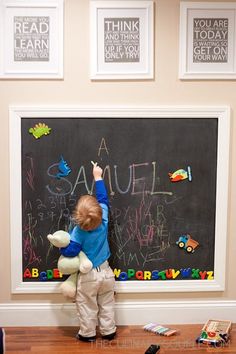 a little boy writing on a chalkboard with his teddy bear