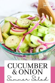 cucumber and onion salad in a glass bowl with a wooden spoon on the side