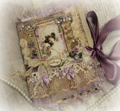 an altered book with lace, pearls and ribbon on it's cover is shown