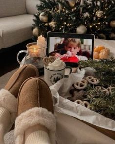 someone is sitting on the floor with their feet up in front of a christmas tree