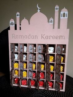 a wooden box filled with chocolates and candies in front of a building that says rama kareem