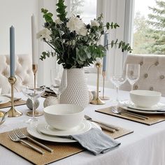 a table set with place settings and flowers in a vase