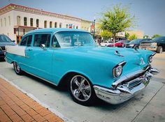 an old blue and white car parked on the street