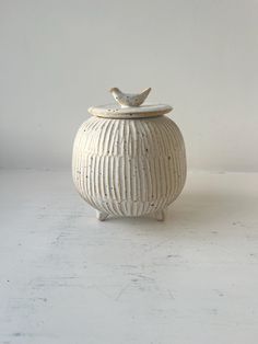 a white ceramic jar with a bird on top