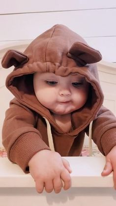 a baby in a bear costume looking over a ledge