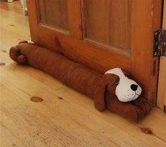 a stuffed dog laying on the floor in front of a door with its head sticking out