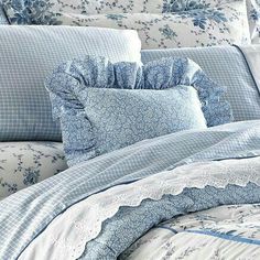 a bed with blue and white comforters, pillows and blankets on top of it