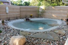 an outdoor hot tub surrounded by rocks and stones in the middle of a backyard area