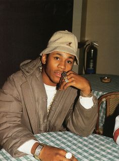 a man sitting at a table with a cell phone in his hand and wearing a hat