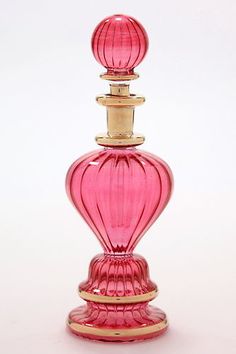 a pink glass perfume bottle sitting on top of a table