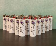 six white flasks with purple flowers and writing on them are lined up next to each other