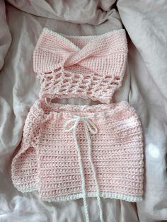 a pink knitted outfit laying on top of a bed