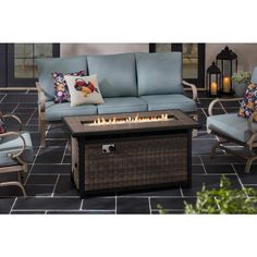 an outdoor fire pit sitting on top of a tile floor next to two chairs and a table