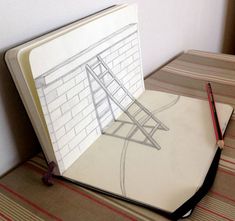 an open book sitting on top of a floor next to a table with a pencil in it