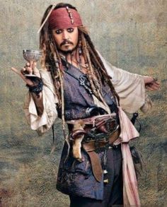 a man with dreadlocks holding a glass in one hand and a pirate hat on the other