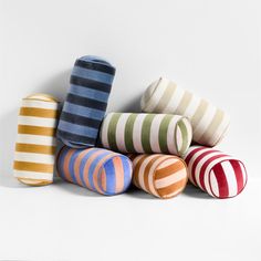 several striped pillows stacked on top of each other in different colors and sizes, all lined up against a white background