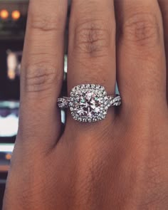 a woman's hand with a diamond ring on top of her finger and the other hand holding an engagement ring