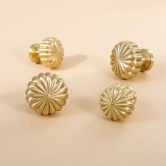 four gold knobs on a white surface with no one in the photo looking at them