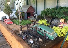 a toy car is parked in a garden with rocks and gravel on the ground next to a house