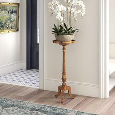 a potted plant sitting on top of a wooden stand next to a door way