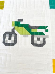 a close up of a quilt with a tractor design on the front and back side