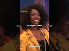 a woman with an afro is smiling and standing in front of a group of people