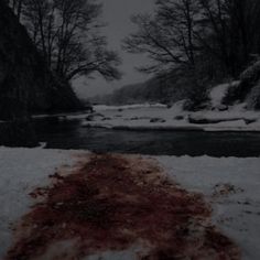 a river with red algae floating on it and trees in the background, surrounded by snow