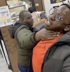 a man with glasses on his head is being hugged by another man in a store