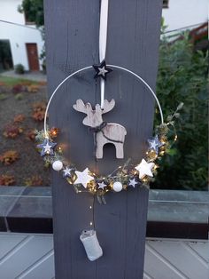 a christmas decoration hanging on the side of a wooden fence with lights and decorations around it