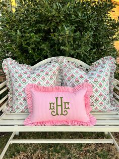 two pillows on a bench with the monogrammed pillow in green, pink and white