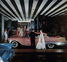 a man and woman standing next to a pink car