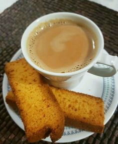 two pieces of bread on a plate next to a cup of coffee