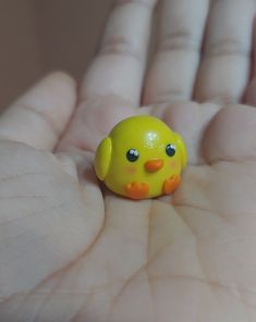 a small yellow toy bird sitting in the palm of someone's hand