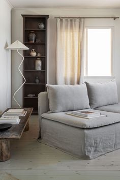 a living room with a couch, book shelf and lamp in it's corner