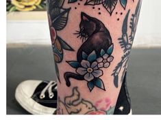 a person with tattoos on their legs has a cat and flowers tattoo on his leg