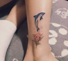 a woman's foot with a dolphin tattoo on her left leg and flowers in the middle