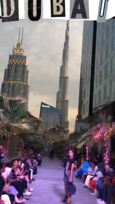 people are sitting on benches in front of tall buildings and the words dubai written across them