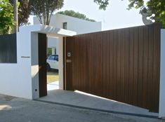 an entrance to a house with a car parked in the driveway and trees behind it