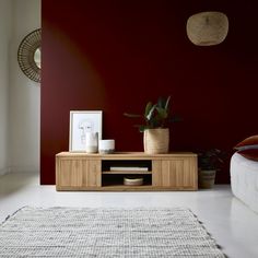 a living room with red walls and white rugs on the floor next to a wooden entertainment center