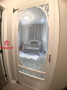 a baby crib is reflected in the mirror of a door that's open