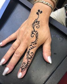 a woman's hand with a henna tattoo on her left wrist and fingers