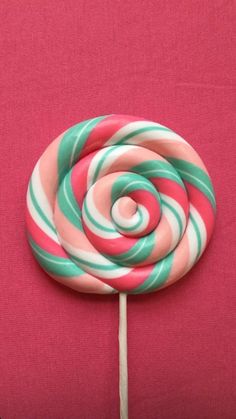 a lollipop on a pink background with green and red swirly candy canes