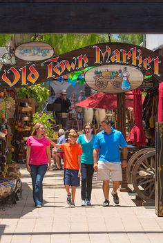 three people walking under a sign that says the town market